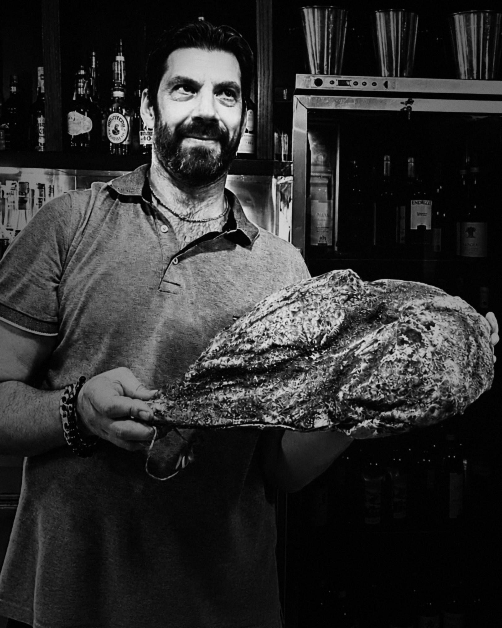 Alessandro, l’oste di Fiore, al bancone del bar con un’ostrica gigante tra le mani