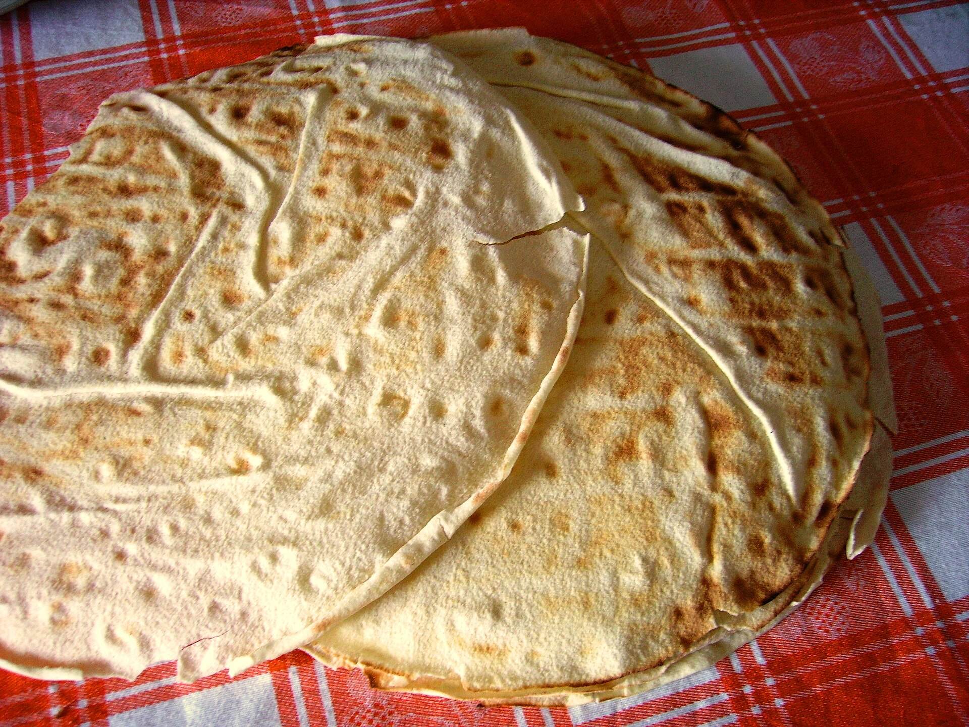 Pila di fogli di pane carasau su una tovaglia a quadri rossi