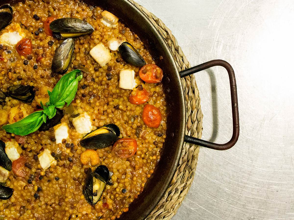 Fregola con cozze, pomodorini e basilico in una padella